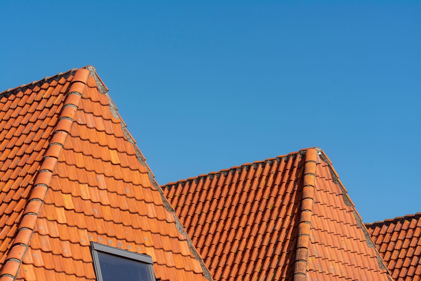 Freshly cleaned red pantile roof against a blue sky